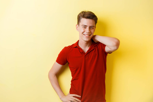 Friendly looking cheerful european guy wearing red shirt smiling standing over yellow background - Φωτογραφία, εικόνα