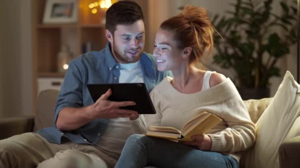 couple with tablet computer and book at home - Кадры, видео