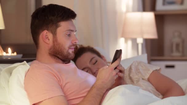 hombre usando el teléfono inteligente mientras su novia está durmiendo
 - Imágenes, Vídeo