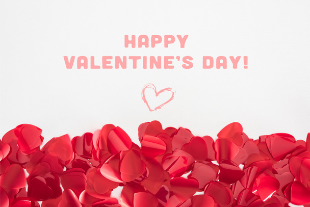 Nahaufnahme schöner roter herzförmiger Blütenblätter auf grauem Hintergrund mit dem Schriftzug "Happy Valentines Day" - Foto, Bild