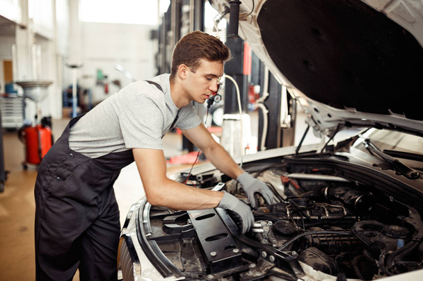 A qualified automechanic is searching for bugs at a car repair service - Photo, Image