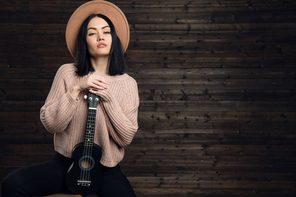 Красивая молодая женщина обнимает свою гитару, одетая в стиле кантри
 - Фото, изображение