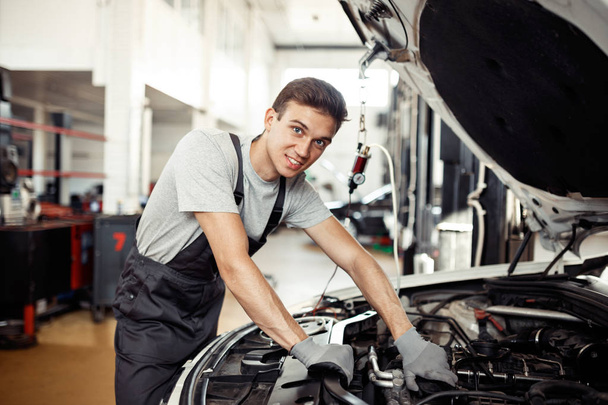An attractive mechanic is at his work repairing a vehicle - Valokuva, kuva