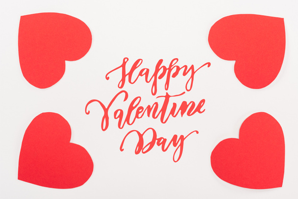 vista superior de tarjetas de papel en forma de corazón rojo aisladas en blanco con letras de "Feliz día de San Valentín"
 - Foto, Imagen