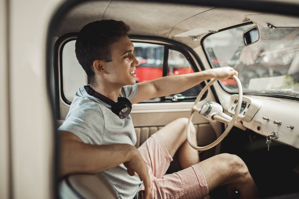 A young and attractive man is driving a vintage car - Fotó, kép