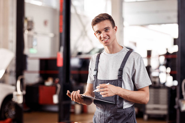An attractive automechanic is smiling while filling in a form - Foto, imagen