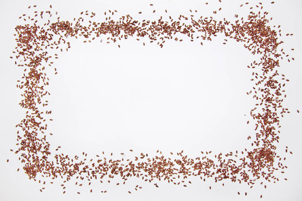 Seeds of flax on sipano along the edges of a frame on a white background with copyspace.. - Photo, image