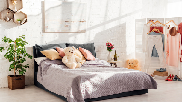 Modernes Interieur des Schlafzimmers mit Teddybär-Spielzeug, Kissen, Pflanzen und Bett - Foto, Bild