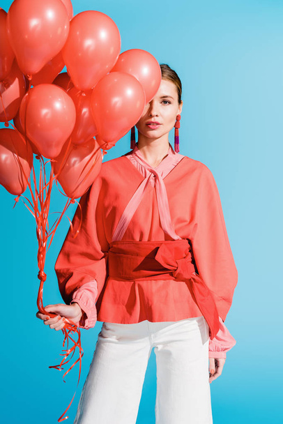 fashionable girl posing with living coral balloons isolated on blue - Foto, Imagem