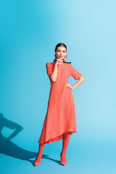 fashion shoot of stylish girl in trendy living coral dress posing on blue - Фото, изображение