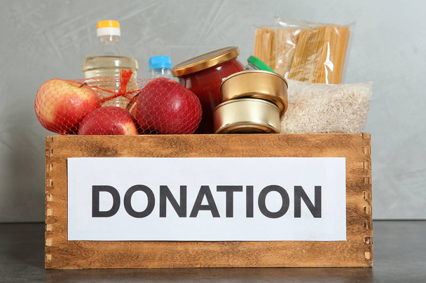 Donation box with food on table against light background - Foto, Imagem