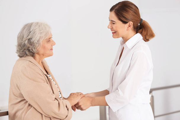 Elderly woman with female caregiver on blurred background - Photo, Image