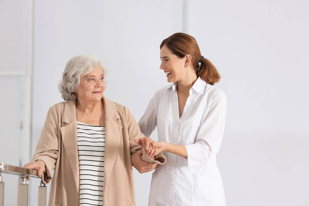 Elderly woman with female caregiver on blurred background - Фото, изображение