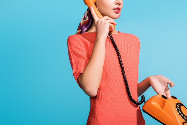 cropped view of girl in living coral dress posing with rotary telephone isolated on blue - Photo, Image