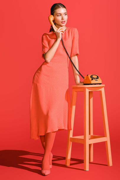 beautiful woman posing with retro rotary telephone on living coral. Pantone color of the year 2019 concept - Foto, Imagem