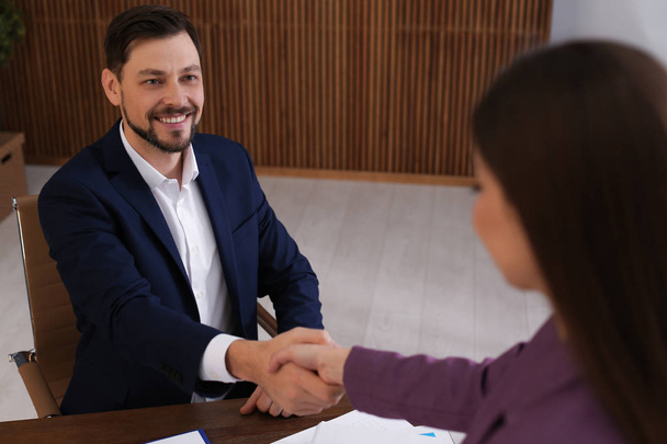 Office employees shaking hands over table with documents at workplace - Foto, immagini