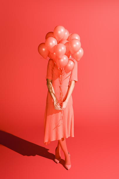 fashionable girl posing with living coral balloons in front of the face. Pantone color of the year 2019 concept - Photo, Image