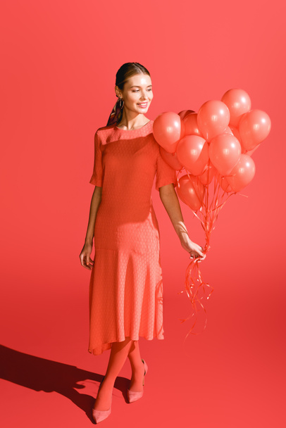 sonriente chica de moda posando con globos de coral vivos. Pantone color del año 2019 concepto
 - Foto, Imagen