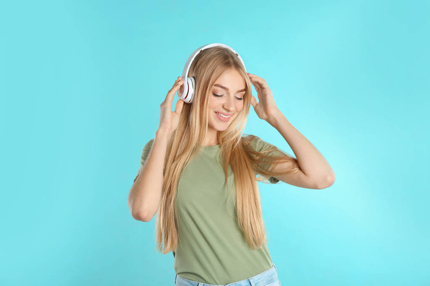 Beautiful young woman listening to music with headphones on white background - Valokuva, kuva
