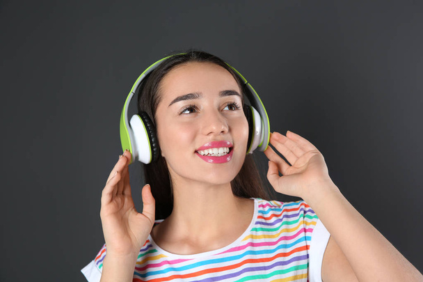 Beautiful young woman listening to music with headphones on black background - Fotoğraf, Görsel