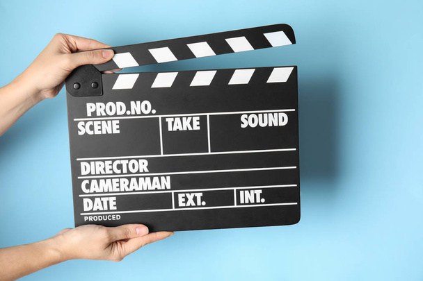 Woman holding clapperboard on color background, closeup. Cinema production - Foto, afbeelding