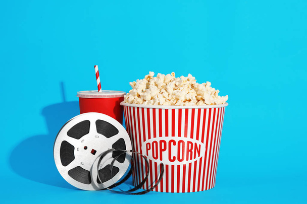 Popcorn, reel and drink on color background. Cinema snack - 写真・画像
