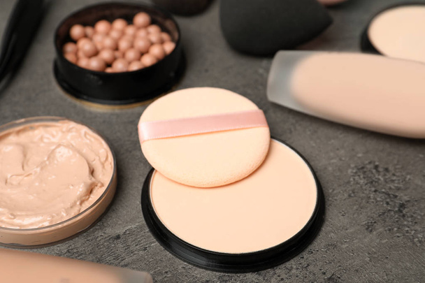 Composition with skin foundation, powder and beauty accessories on grey background - Foto, Bild
