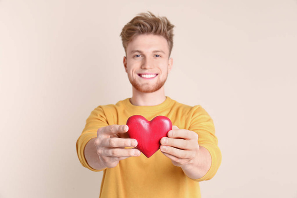 Portrait of young man with decorative heart on color background - 写真・画像