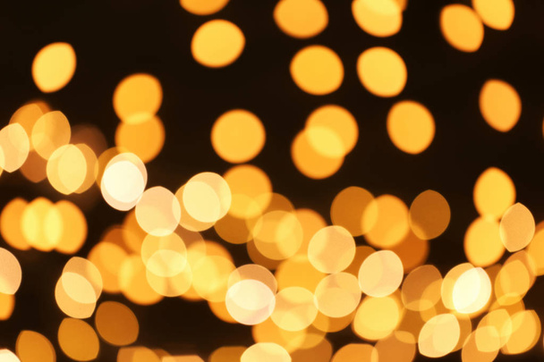 Beautiful golden lights on dark background. Bokeh effect - Photo, Image
