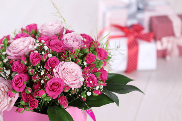 Beautiful bouquet of flowers and blurred gifts on background. Space for text - Zdjęcie, obraz