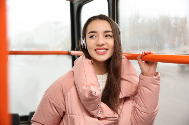 Beautiful young woman listening to music with headphones in public transport - Photo, image