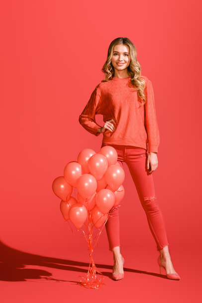 smiling stylish girl posing with living coral balloons. Pantone color of the year 2019 concept - Foto, imagen