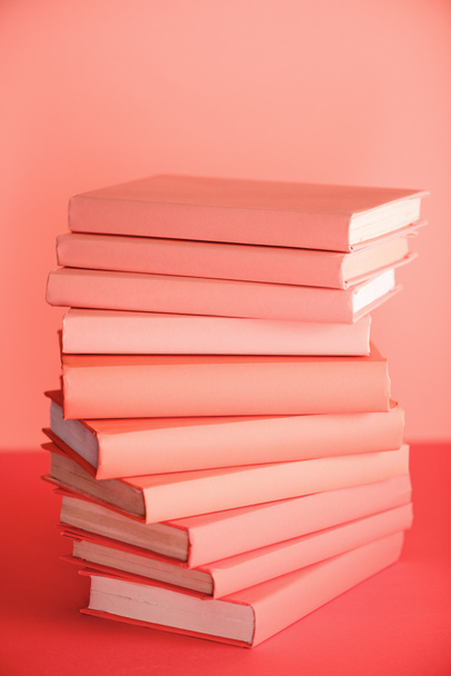 stack of books on living coral background. Pantone color of the year 2019 concept - Photo, Image