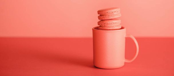sweet macarons in cup on trendy Living coral background. Pantone color of the year 2019 concept - Photo, Image