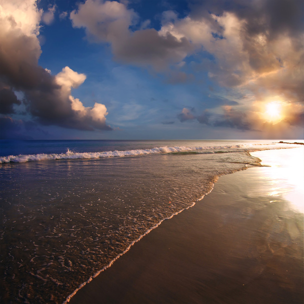 Tropical design postcard. Beautiful sunset on sand beach with sea foam and cloudy sky - Foto, Imagen