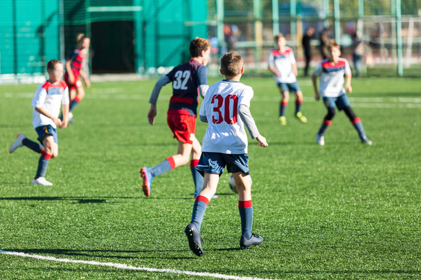 Хлопці з червоно-білого спортивного одягу бігають на футбольному полі. Молоді футболісти грають у футбол і кидають м'яч. Тренінг, активний спосіб життя, спорт, концепція дитячої діяльності
  - Фото, зображення