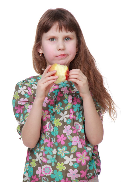 Llittle girl with long hair in colorful clothes eating an apple - Фото, изображение
