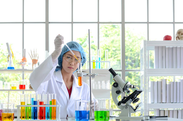 A nő tudós laboratóriumban csinálás kísérletek által egységesítési vegyületek használata a Cseppentő, egy kémcsőbe. Fénykép fogalmának egészségügyi orvostechnológiai és gyógyszeripari kutatás és fejlesztés. - Fotó, kép