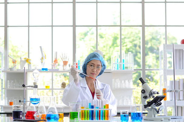 La femme scientifique en laboratoire faisant des expériences en synthétisant des composés avec utilisation d'un compte-gouttes dans une éprouvette
. - Photo, image