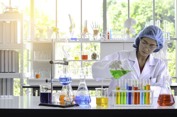 La ricercatrice scienziata donna in laboratorio che tiene una soluzione liquida e versa in provetta in un laboratorio
. - Foto, immagini