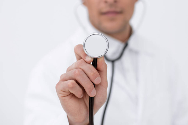 Lächelnder Arzt zeigt Stethoskop - Foto, Bild