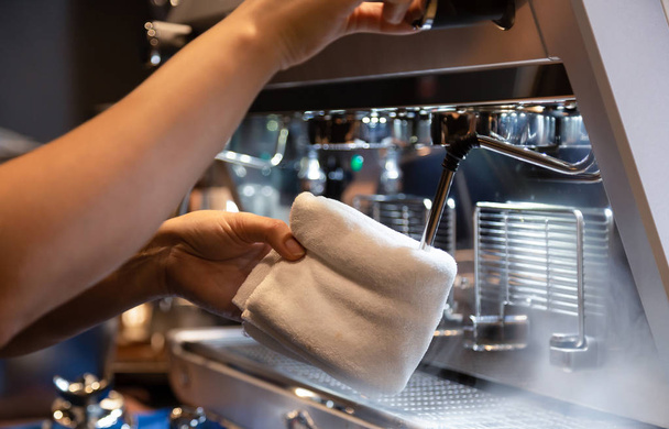 Hand of barista cleaning milk frother of coffee machine to be ready for milk frothing at coffee shop - Photo, Image