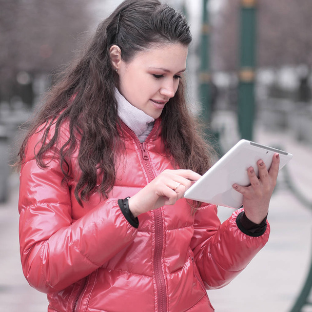 young woman with digital tablet on city background - Foto, afbeelding