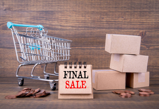 Final sale concept. Paper boxes, shopping cart on wooden background - Photo, Image