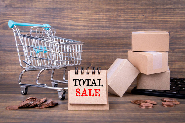 Total Sale concept. Paper boxes, shopping cart and computer keyboard on wooden background - Photo, Image