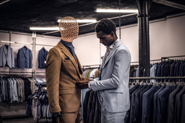 Elegancko ubrany mężczyzna African-American pracę w sklepie klasycznej odzieży męskiej. - Zdjęcie, obraz