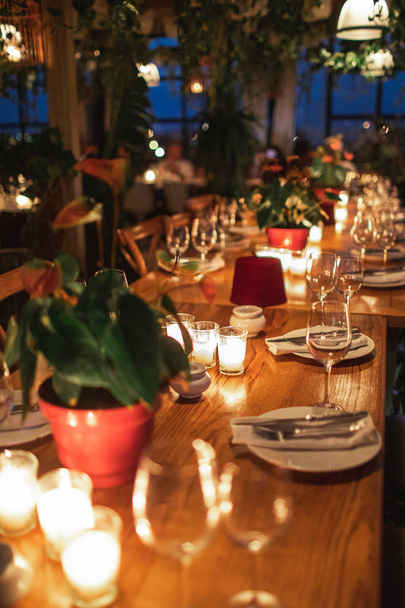 Primer plano de la mesa decorada sin gente. Mesa de comedor con platos, copas de vino y velas
. - Foto, imagen