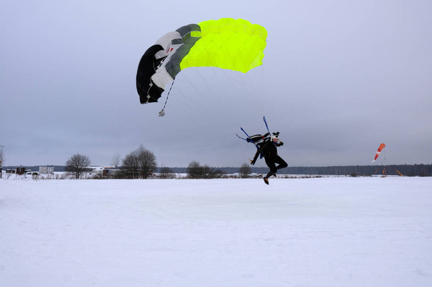 Χειμερινή σεζόν. Μια skydiver είναι η προσγείωση σε χιονισμένο πεδίο. - Φωτογραφία, εικόνα