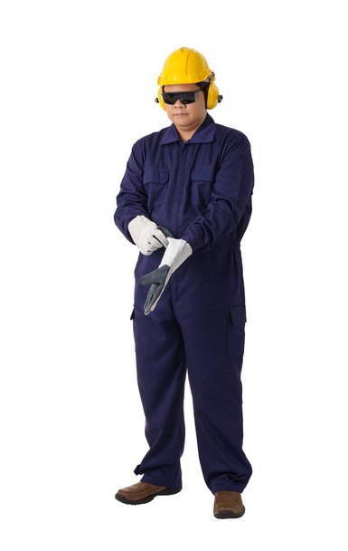 portret pracownika w kombinezon mechanika jest usuwanie lub noszenie ochronnych rękawice z kask, nauszniki i okulary ochronne na białym tle na białym tle obrzynek ścieżka - Zdjęcie, obraz