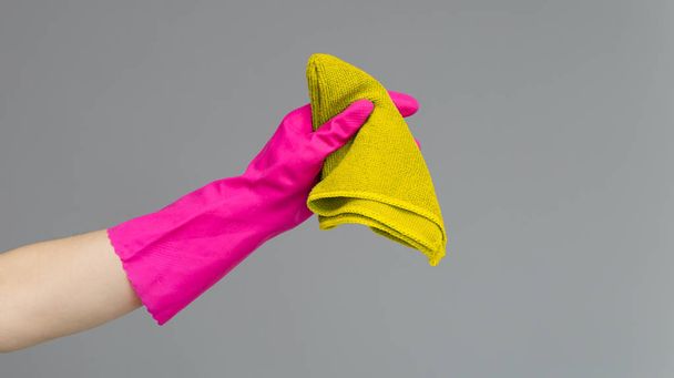 Hand in a rubber glove holds a bright microfiber duster on a neutral background. Spring cleaning concept. - Fotografie, Obrázek